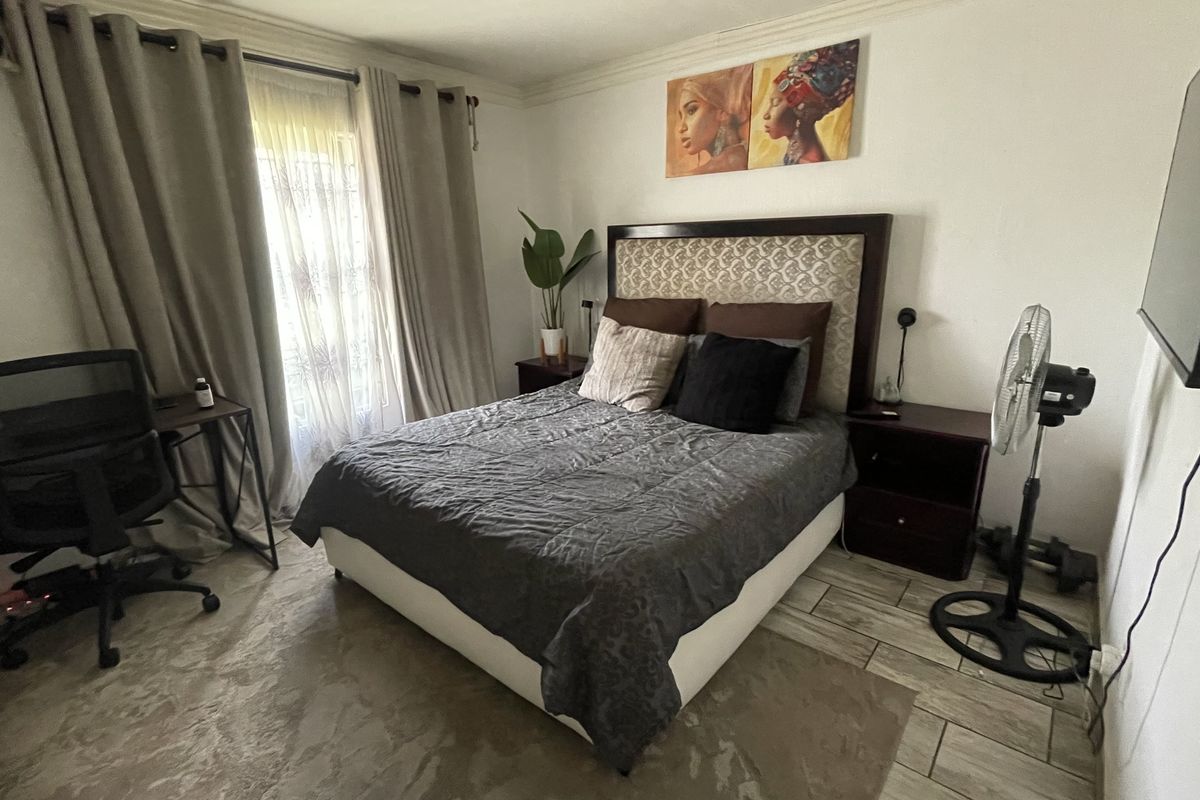 A functional bedroom featuring tiled flooring and natural light through a window with curtain rails.