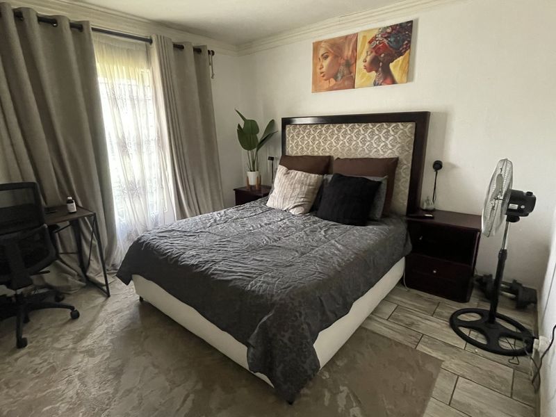 A functional bedroom featuring tiled flooring and natural light through a window with curtain rails.