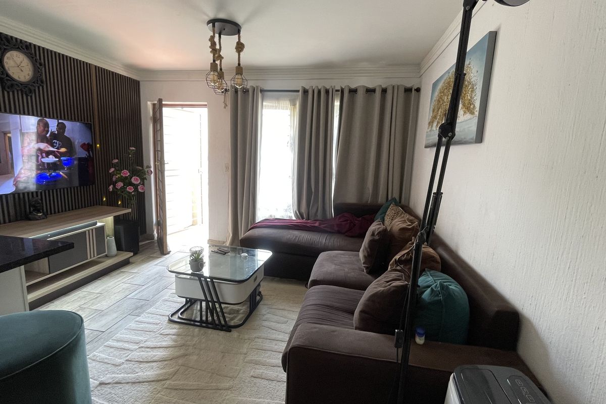 A cozy living room featuring a decorative slatted wood accent wall, tiled flooring, and crown molding, providing a comfortable and well-maintained living space.