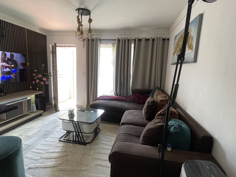 A cozy living room featuring a decorative slatted wood accent wall, tiled flooring, and crown molding, providing a comfortable and well-maintained living space.