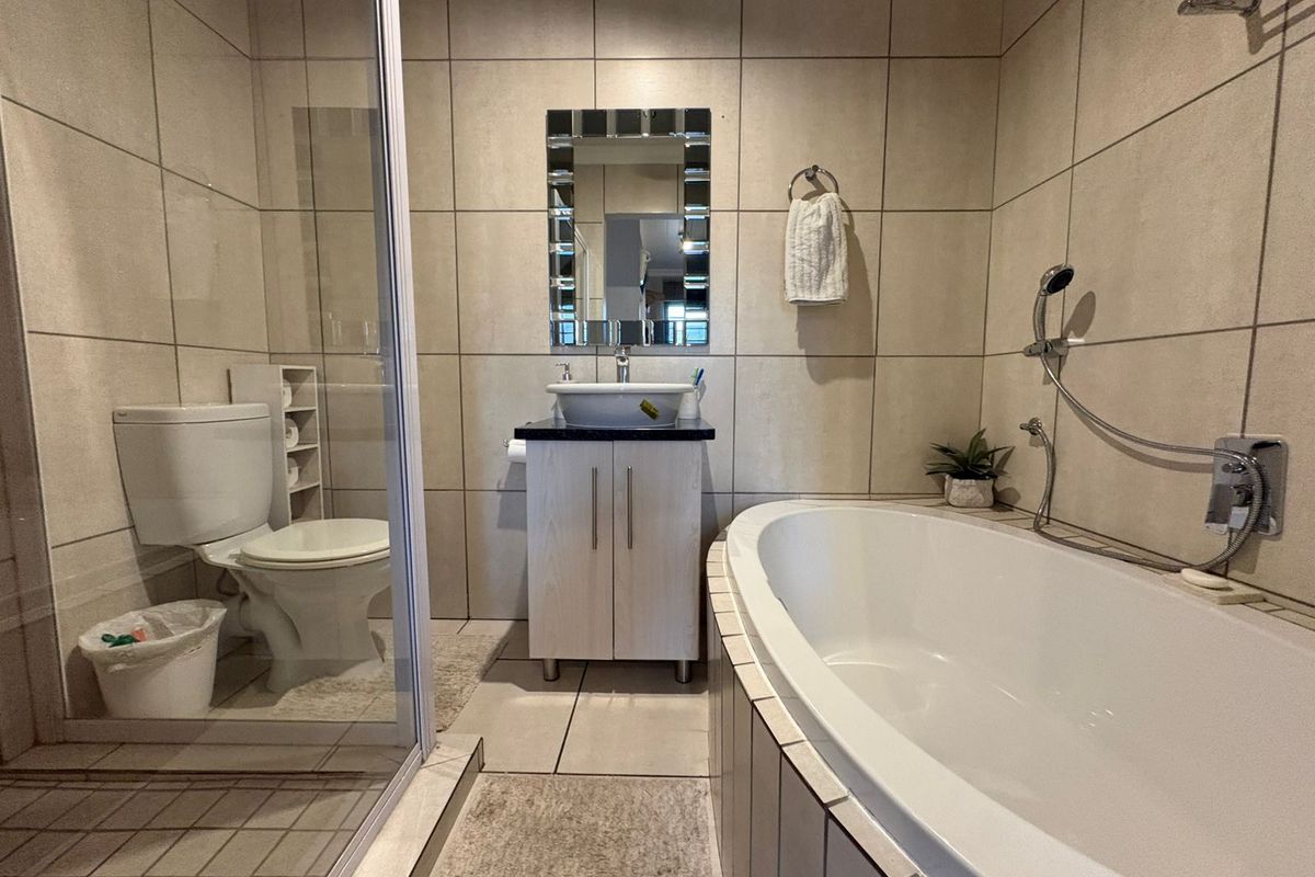 A modern bathroom featuring a tiled walk-in shower, a freestanding bathtub, and a vanity unit with a vessel sink.