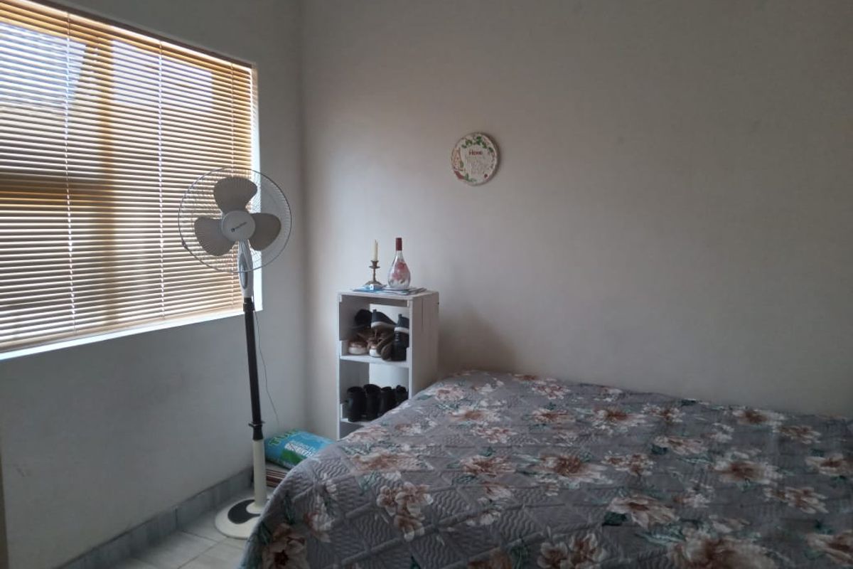 A functional bedroom featuring tiled flooring and venetian blinds, providing a neutral base for personalization.