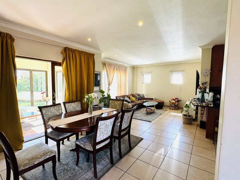 Spacious open-plan living and dining area featuring tiled flooring, recessed lighting, and large sliding glass doors providing access to the outdoor patio.