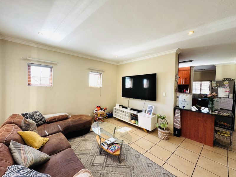 Open-plan living area featuring tiled flooring, recessed lighting, and a connected kitchen space with a breakfast bar.