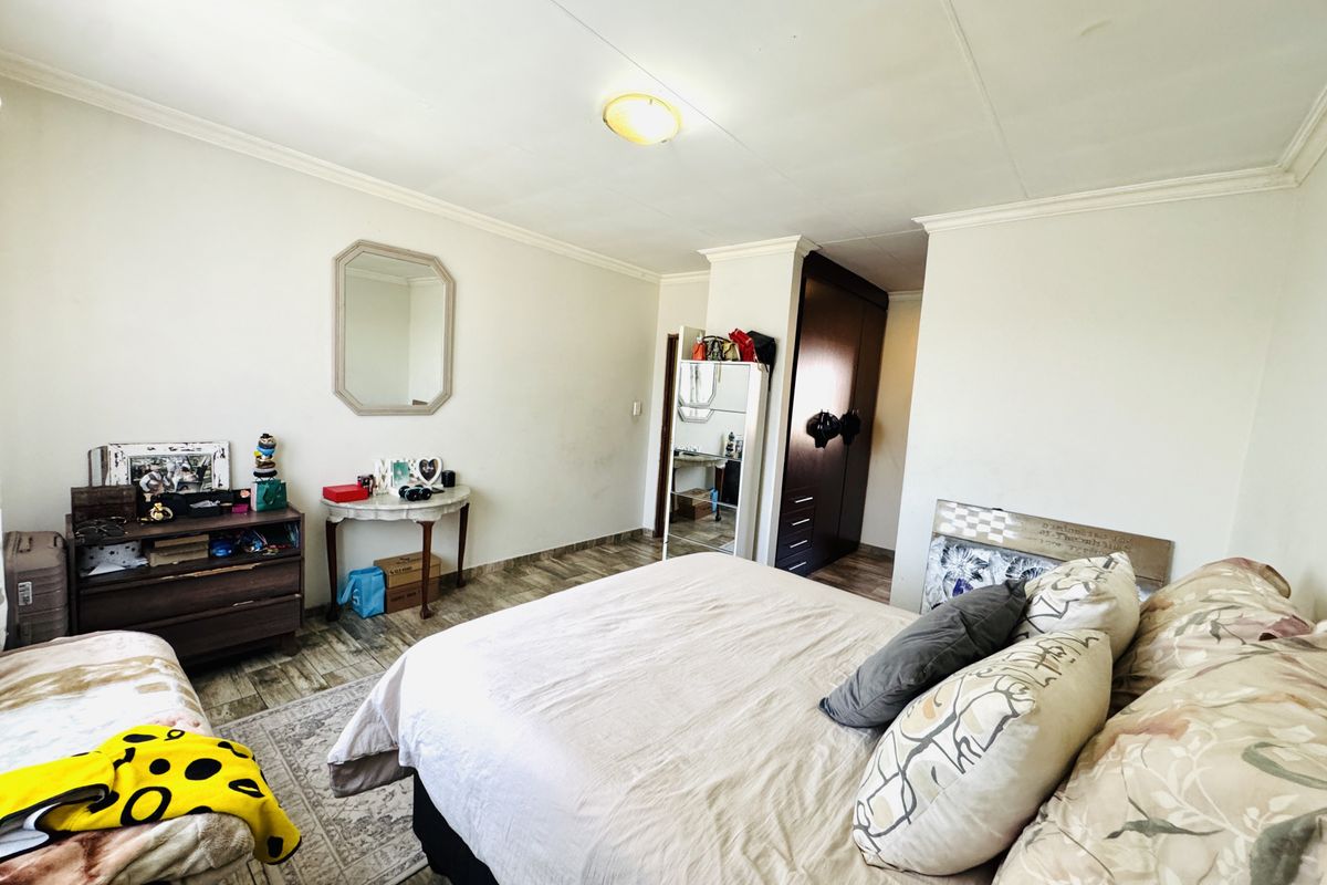 A functional bedroom featuring tiled flooring, built-in wardrobe storage, and ceiling cornice detailing.