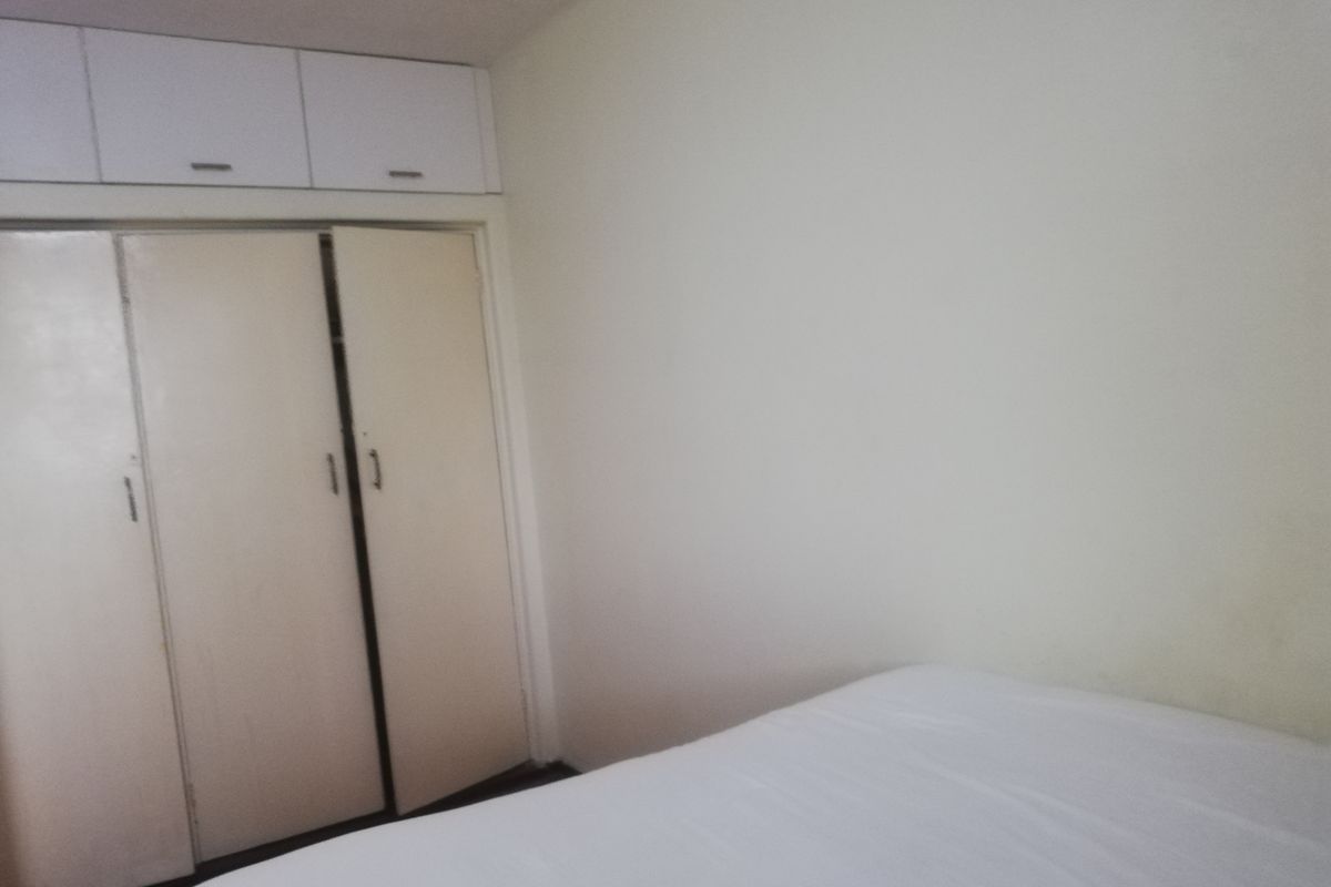 A bedroom featuring built-in cupboards with overhead storage units, providing functional storage space within the room.
