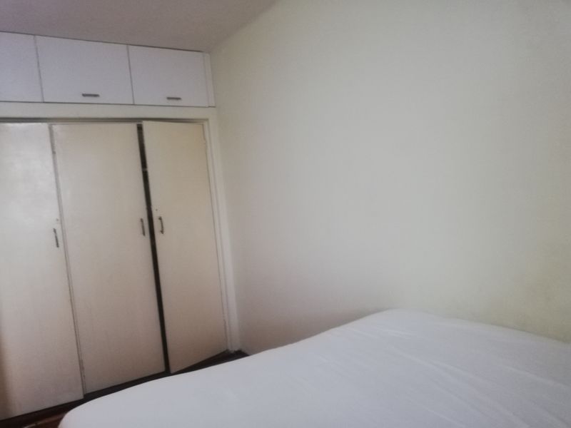 A bedroom featuring built-in cupboards with overhead storage units, providing functional storage space within the room.