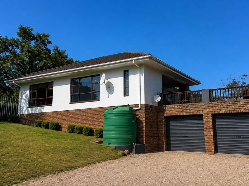 A well-maintained house exterior featuring a brick and white facade, double garage with roller doors, and a raised deck area.