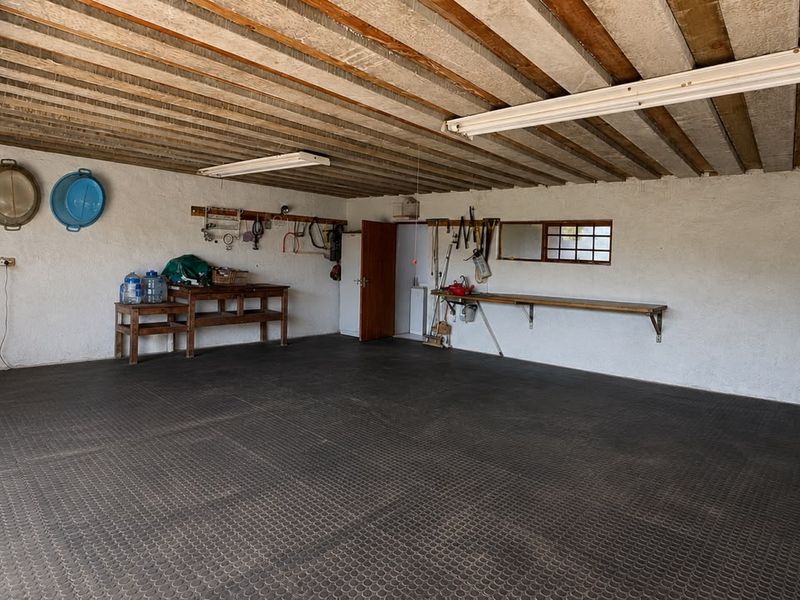 Spacious garage featuring exposed beam ceilings, durable rubber flooring, and built-in wall-mounted workbenches, offering ample storage or workshop potential.