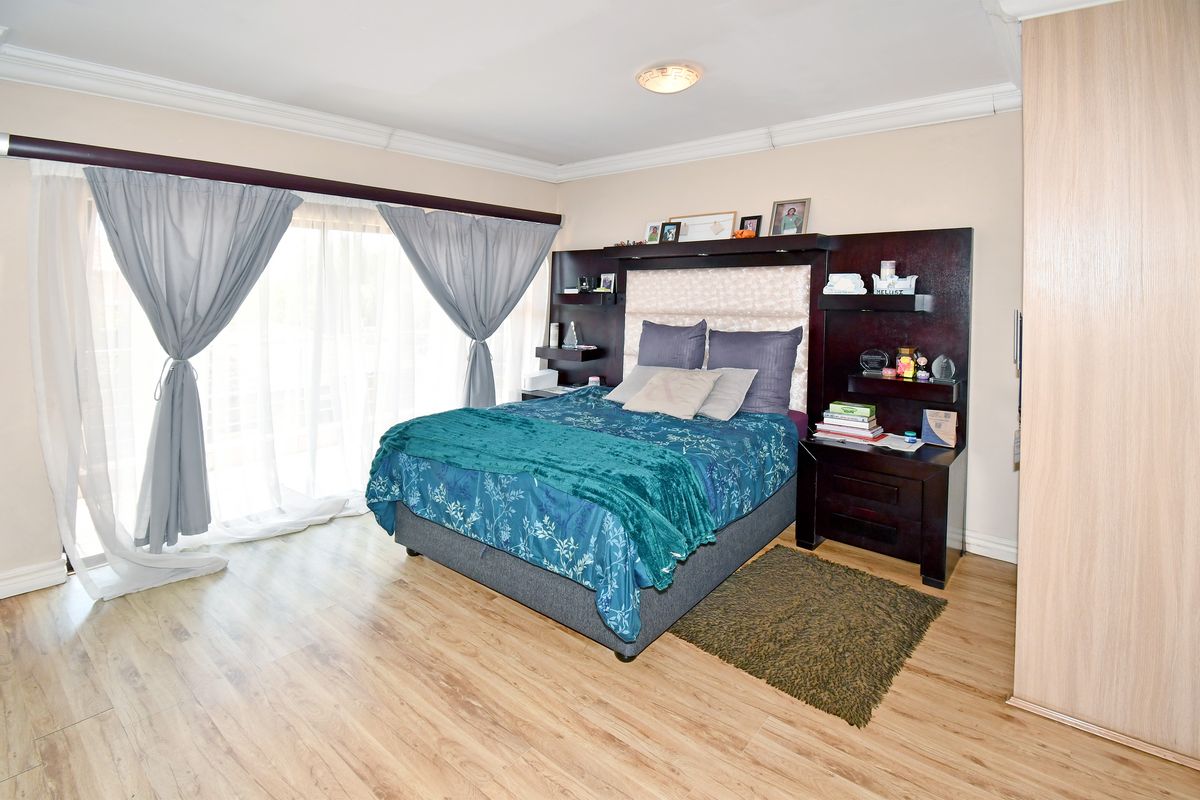A well-maintained bedroom featuring laminate flooring, a built-in headboard with integrated shelving, and sliding glass doors providing access to the exterior.
