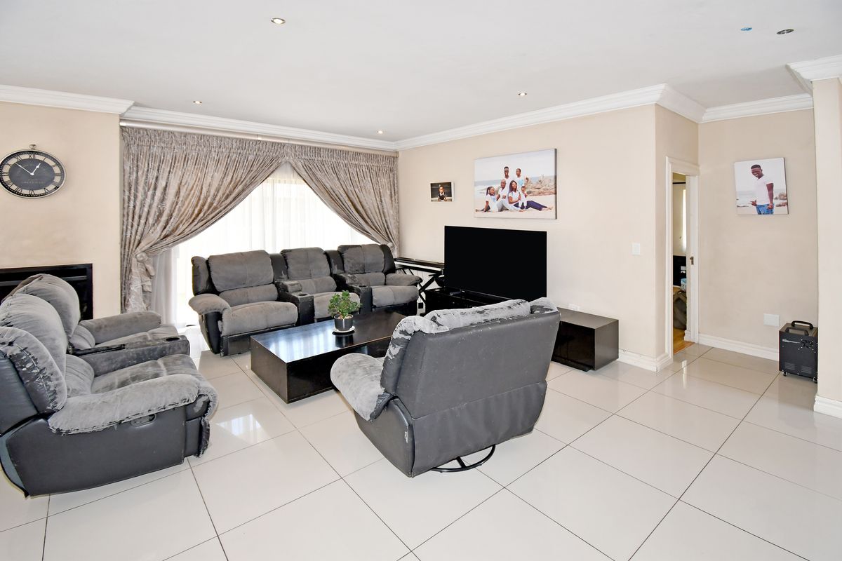 Spacious living room featuring neutral tiled flooring, recessed downlighting, and coved cornicing, with large sliding doors providing access to the exterior.