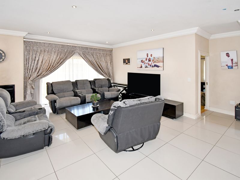Spacious living room featuring neutral tiled flooring, recessed downlighting, and coved cornicing, with large sliding doors providing access to the exterior.