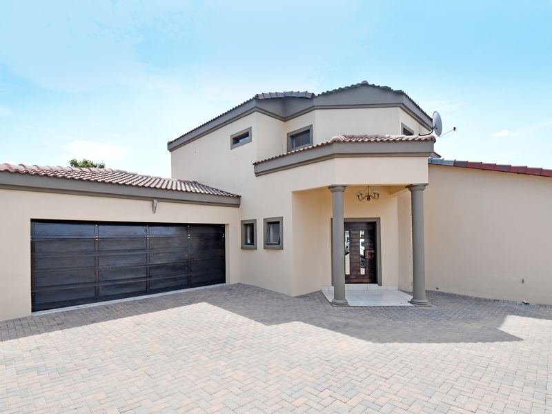 Front elevation of a modern double-story home featuring a paved driveway, double garage, and a covered entrance with decorative columns.