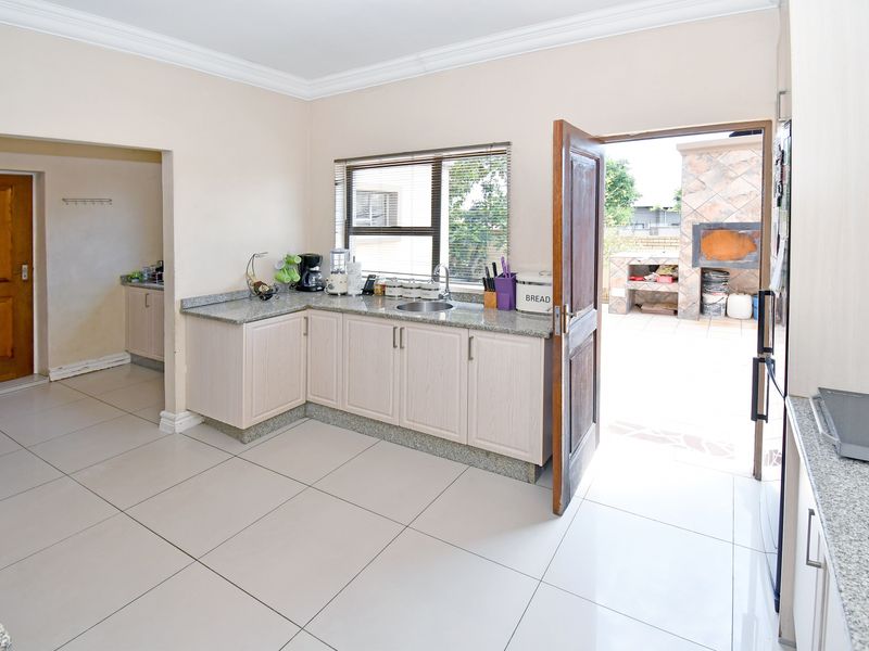 A functional kitchen featuring granite countertops, ample cabinetry, and tiled flooring, with direct access to an outdoor patio area.
