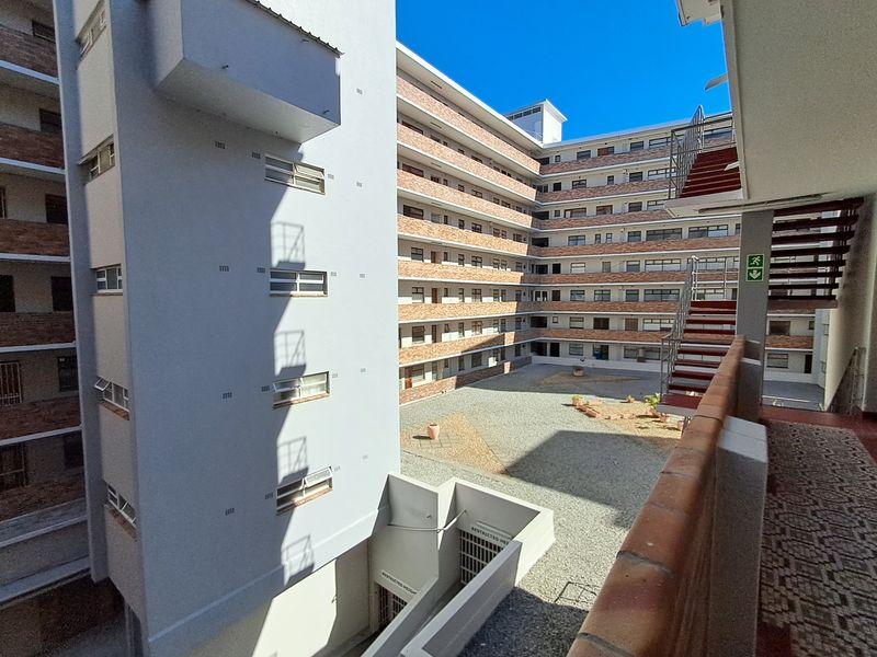 View of the apartment complex courtyard featuring a gravel ground area, brick facade, and external metal staircases.