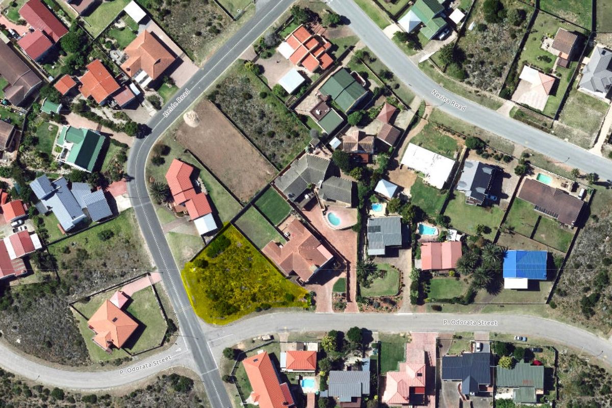 An aerial view of a vacant residential plot situated on a corner lot in a developed suburban neighborhood.