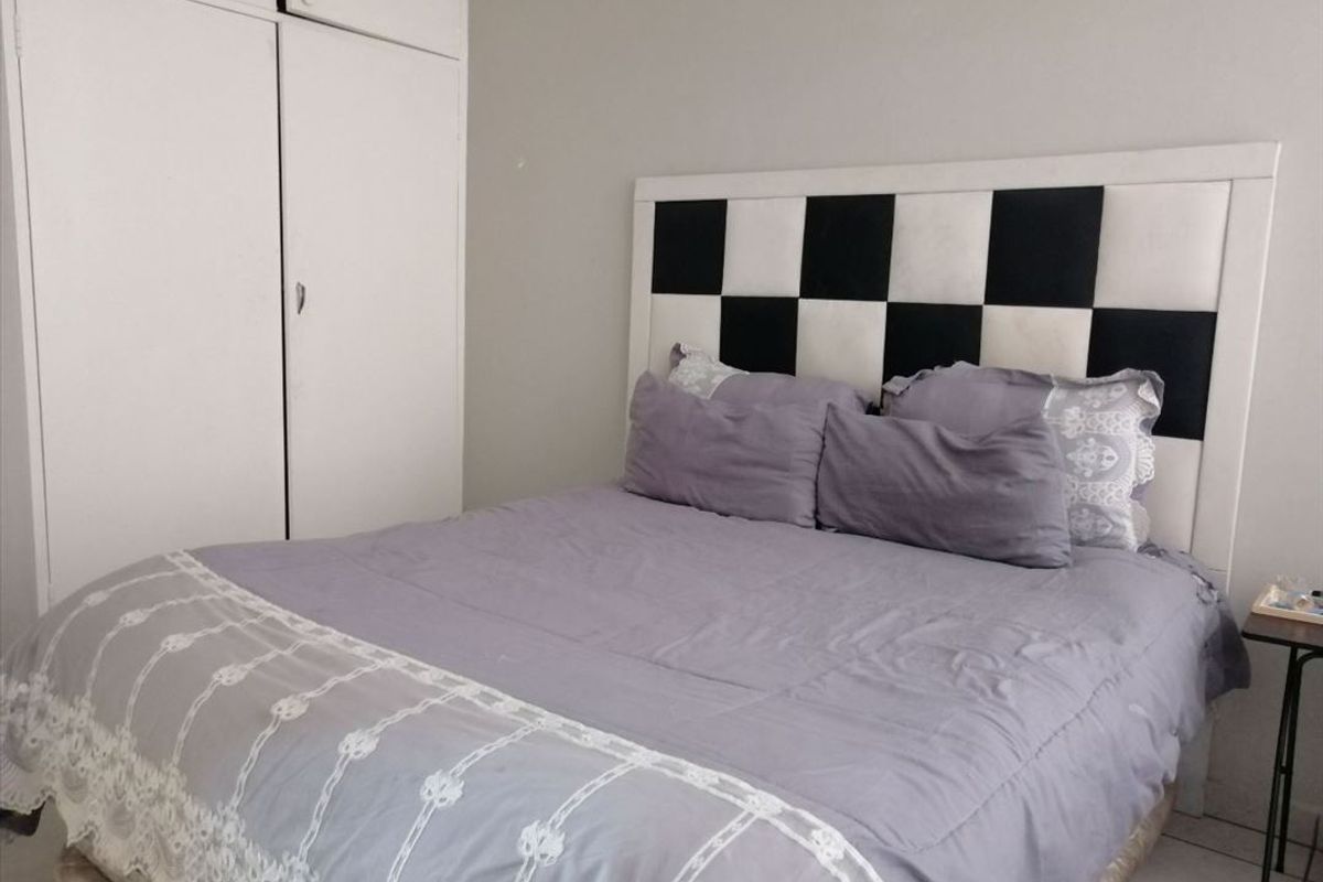 A bedroom featuring built-in cupboards and tiled flooring, providing a functional space for rest.