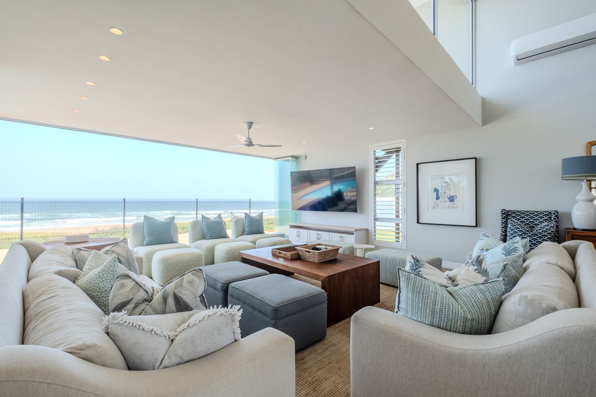 Spacious open-plan living area featuring high ceilings, recessed lighting, and seamless indoor-outdoor flow to a balcony with panoramic ocean views.