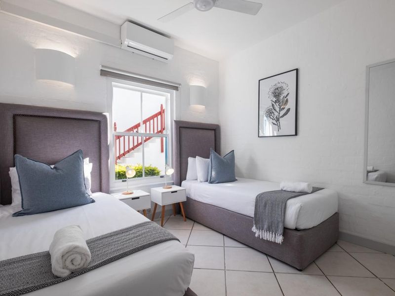 A well-maintained bedroom featuring tiled flooring, a ceiling fan, and a split-system air conditioner, with natural light provided by a sash window.
