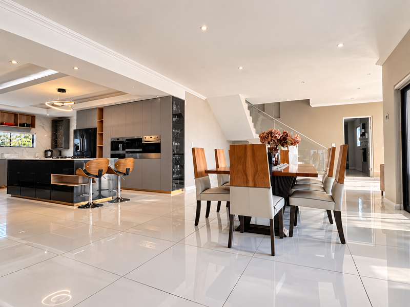 Spacious open-plan living area featuring a modern kitchen with integrated appliances, a central island, and seamless flow to the outdoor patio through sliding doors.