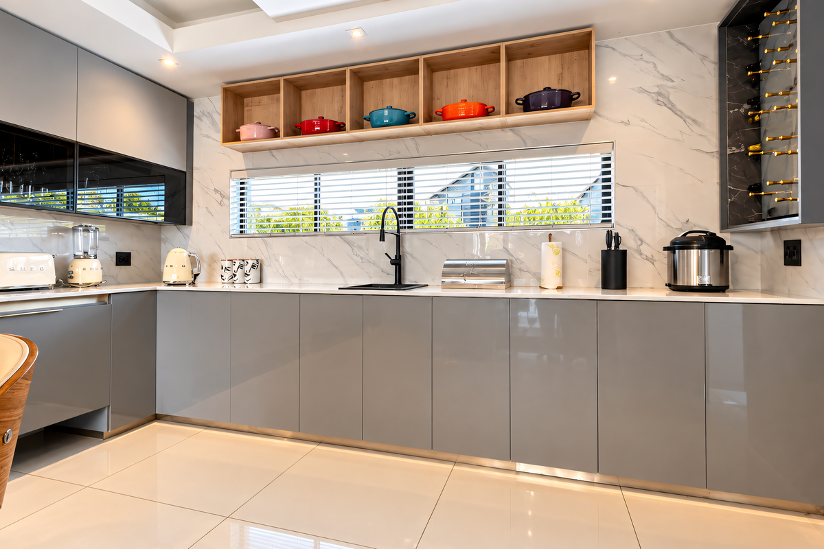 Modern kitchen featuring high-gloss grey cabinetry, marble-look splashback, integrated wine storage, and open timber shelving with sleek contemporary finishes.