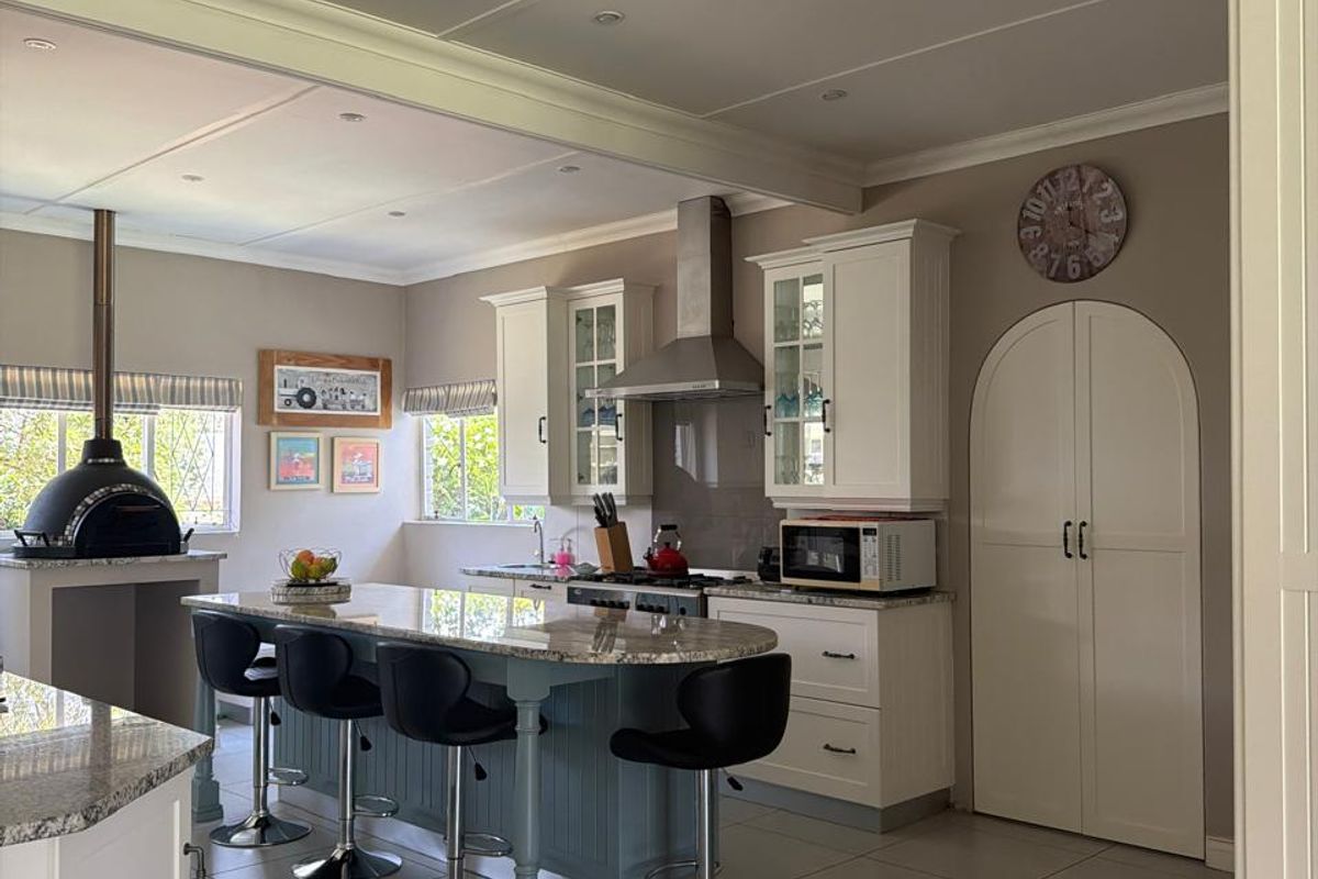 Spacious kitchen featuring a central island with granite countertops, built-in cabinetry, stainless steel extractor fan, and a unique integrated pizza oven.