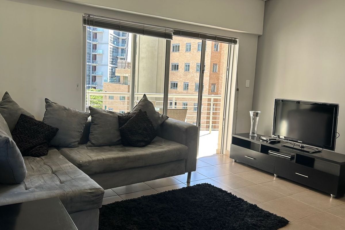 A well-lit living room featuring tiled flooring and a large sliding glass door that opens onto a balcony with urban views.