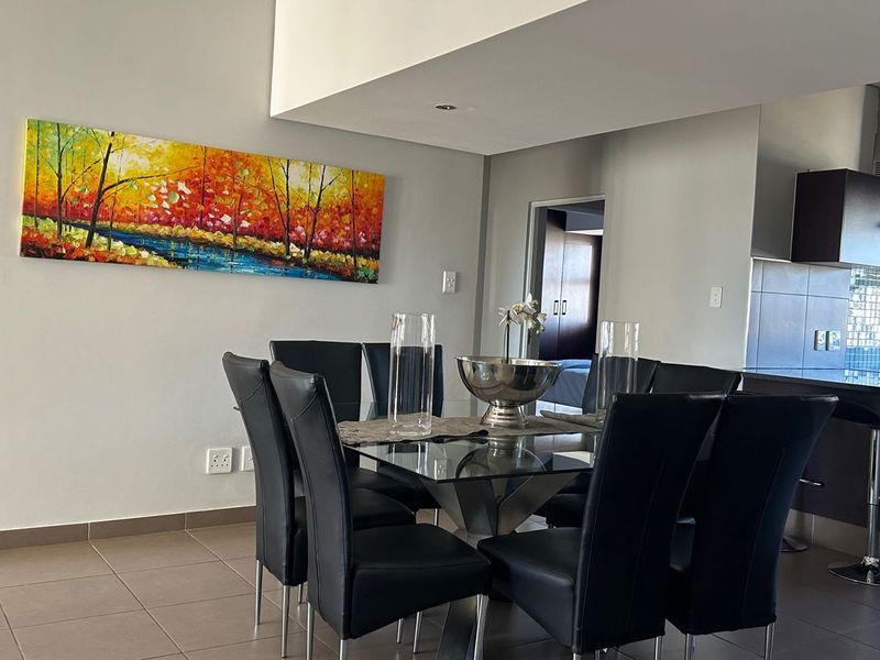 Open-plan living and dining area featuring tiled floors, recessed lighting, and a modern kitchen with built-in cabinetry and an extractor fan.