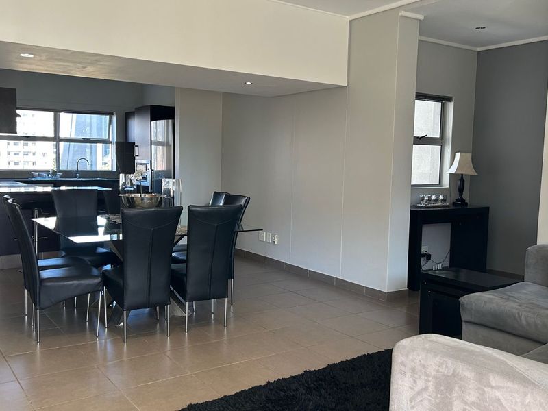 Spacious open-plan living and dining area featuring tiled floors, recessed lighting, and a functional kitchen with built-in cabinetry and counter space.