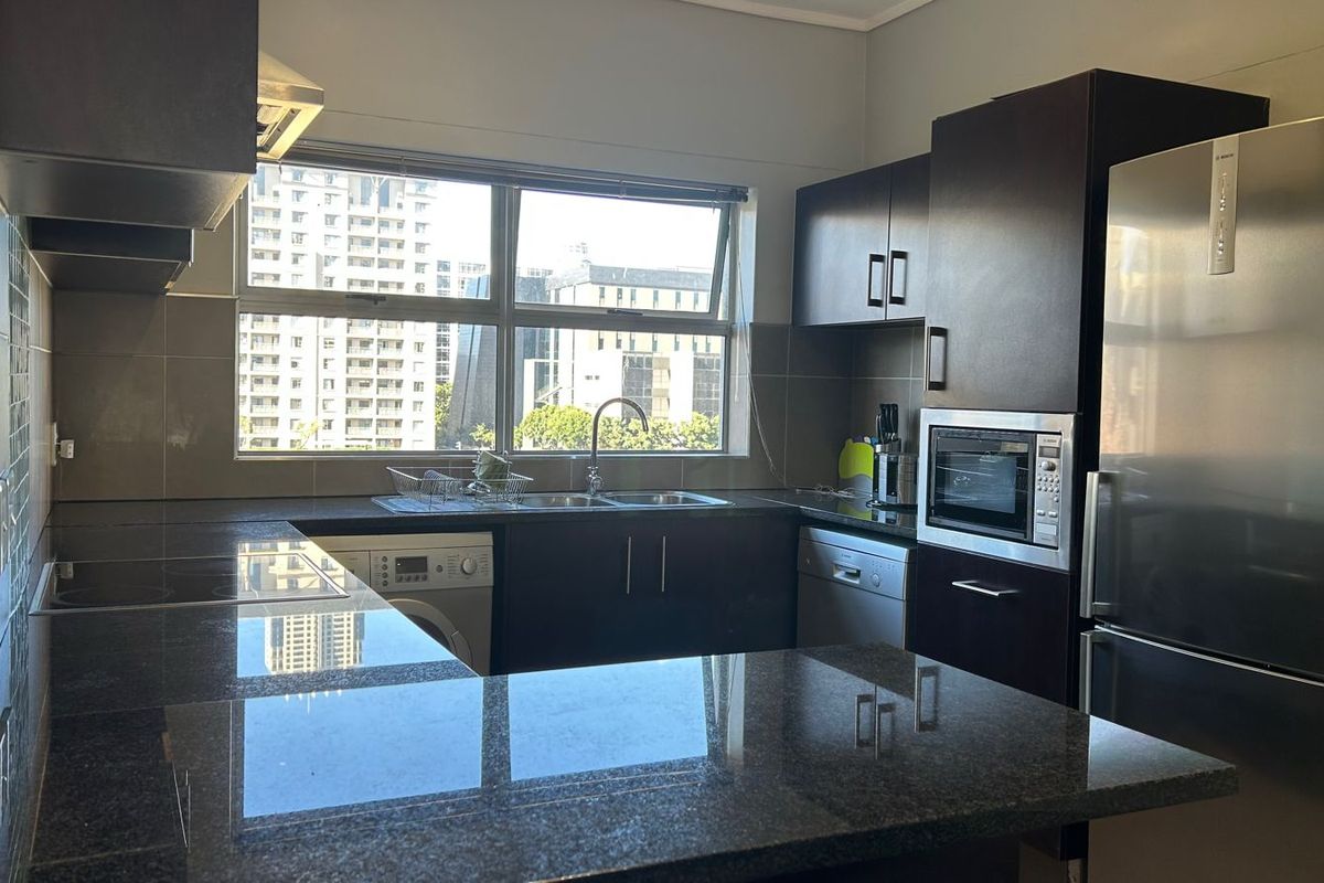 Modern kitchen featuring dark wood cabinetry, granite countertops, tiled backsplash, and integrated appliances, offering a functional and sleek workspace with city views.