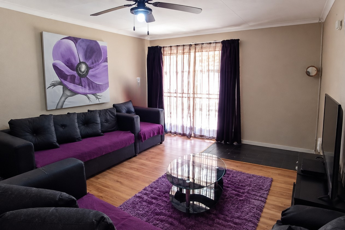 A comfortable living room featuring laminate flooring, a ceiling fan, and a sliding glass door that provides natural light.