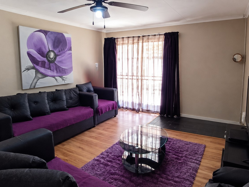 A comfortable living room featuring laminate flooring, a ceiling fan, and a sliding glass door that provides natural light.