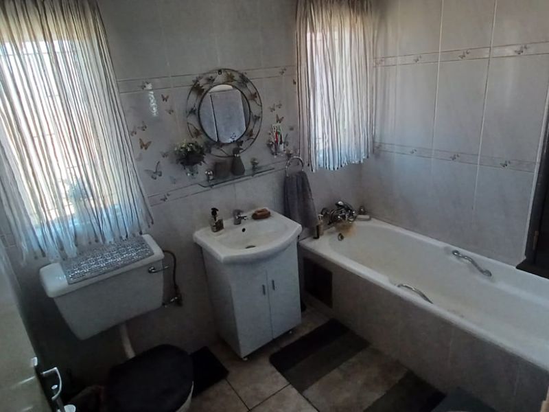 A functional bathroom featuring a bathtub, vanity basin, and toilet with tiled wall finishes.