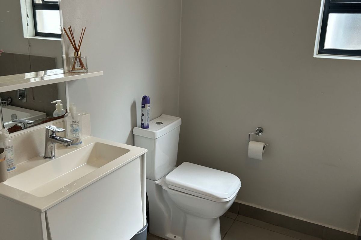 A clean and functional bathroom featuring a modern vanity with basin, a wall-mounted mirror, and a standard toilet suite.