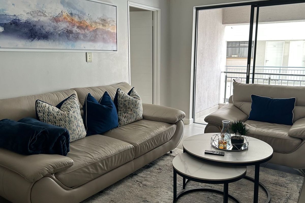 A bright living room featuring tiled flooring and a large sliding glass door that provides access to an outdoor balcony area.