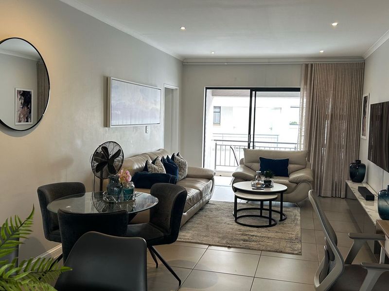 A well-maintained open-plan living and dining area featuring tiled floors, recessed lighting, and a sliding glass door leading to a balcony.