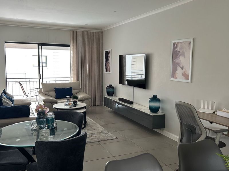 Spacious open-plan living area featuring neutral tiled flooring, recessed lighting, and a large sliding glass door leading to a balcony.