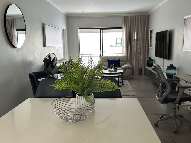 Spacious open-plan living and dining area featuring tiled flooring, recessed lighting, and a large sliding glass door leading to an outdoor balcony.