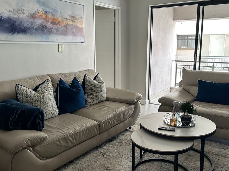 A bright living room featuring tiled flooring and a large sliding glass door that provides access to an outdoor balcony area.