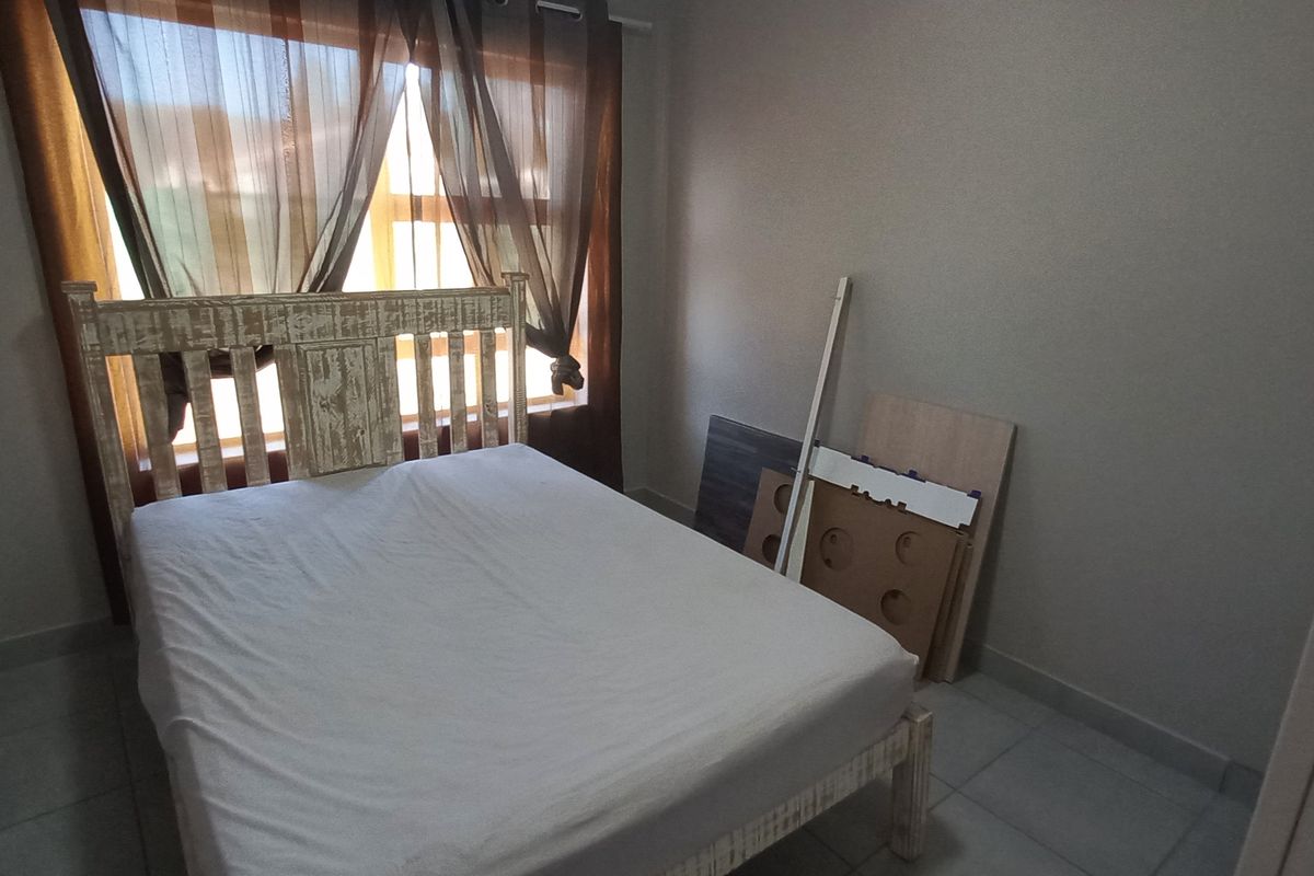 A standard bedroom featuring tiled flooring and a large window with curtains, providing a functional space for rest.