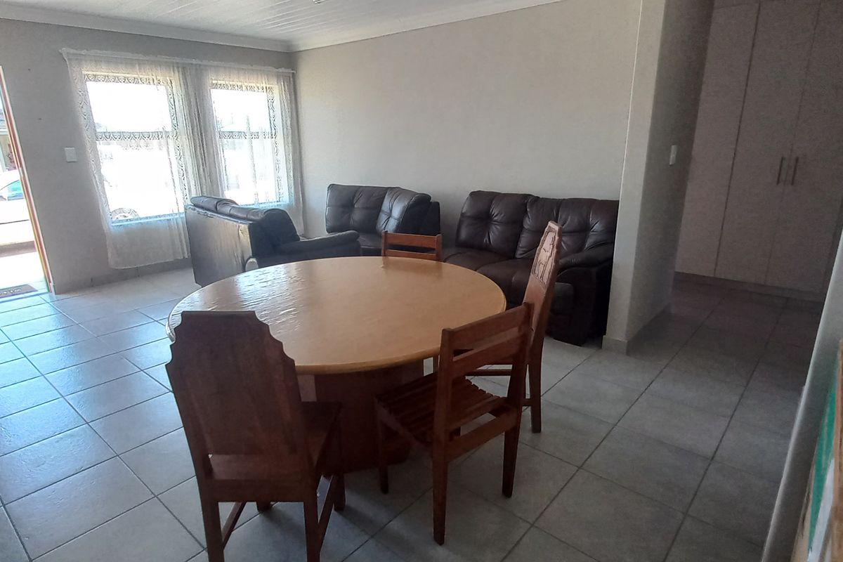 A spacious living area featuring neutral tiled flooring, coved ceilings, and built-in storage cupboards, with direct access to the exterior.