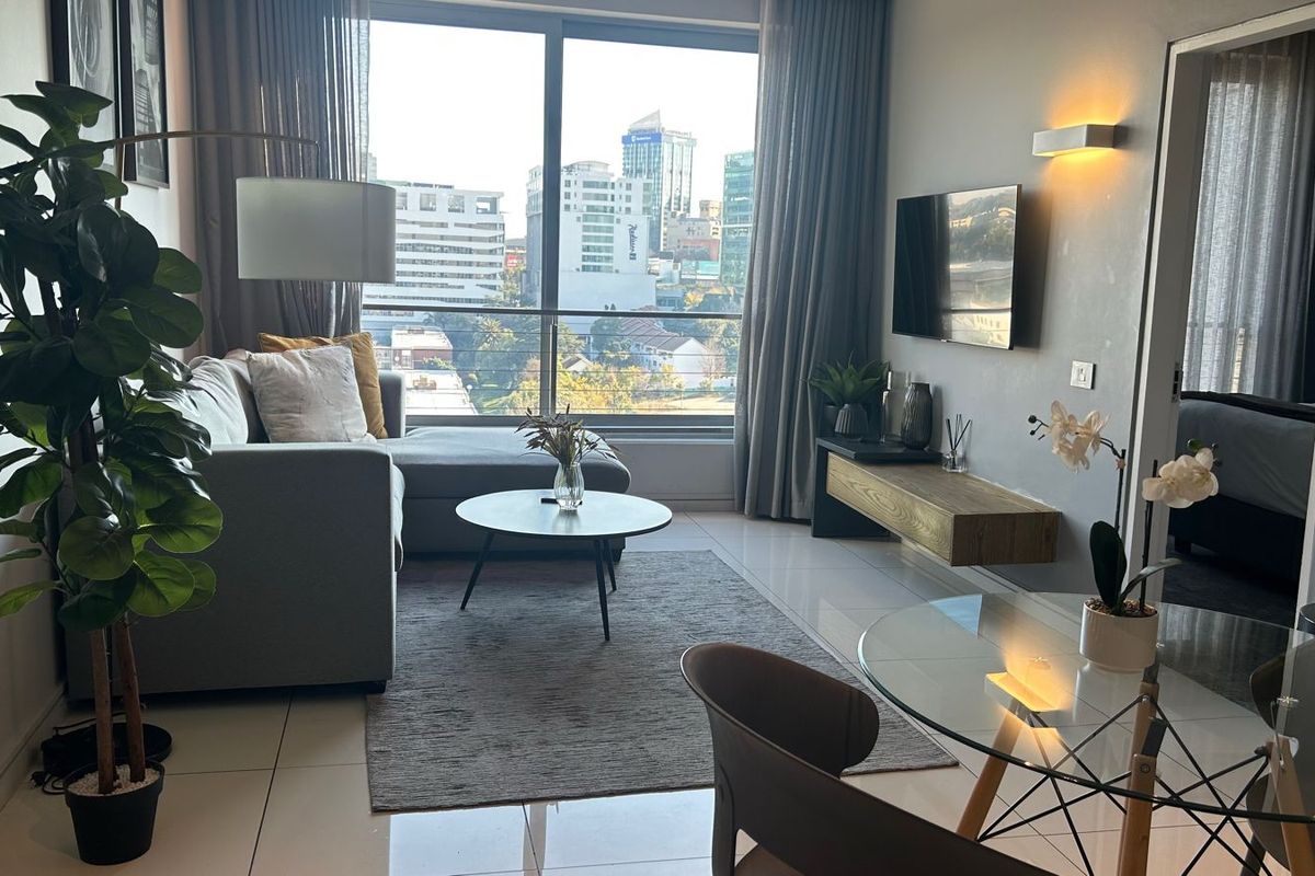 Modern living room featuring large floor-to-ceiling windows with city views, tiled flooring, and a sleek floating media console.