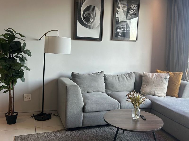 A well-maintained living room featuring tiled flooring and a large window with natural light, offering a comfortable and modern living space.