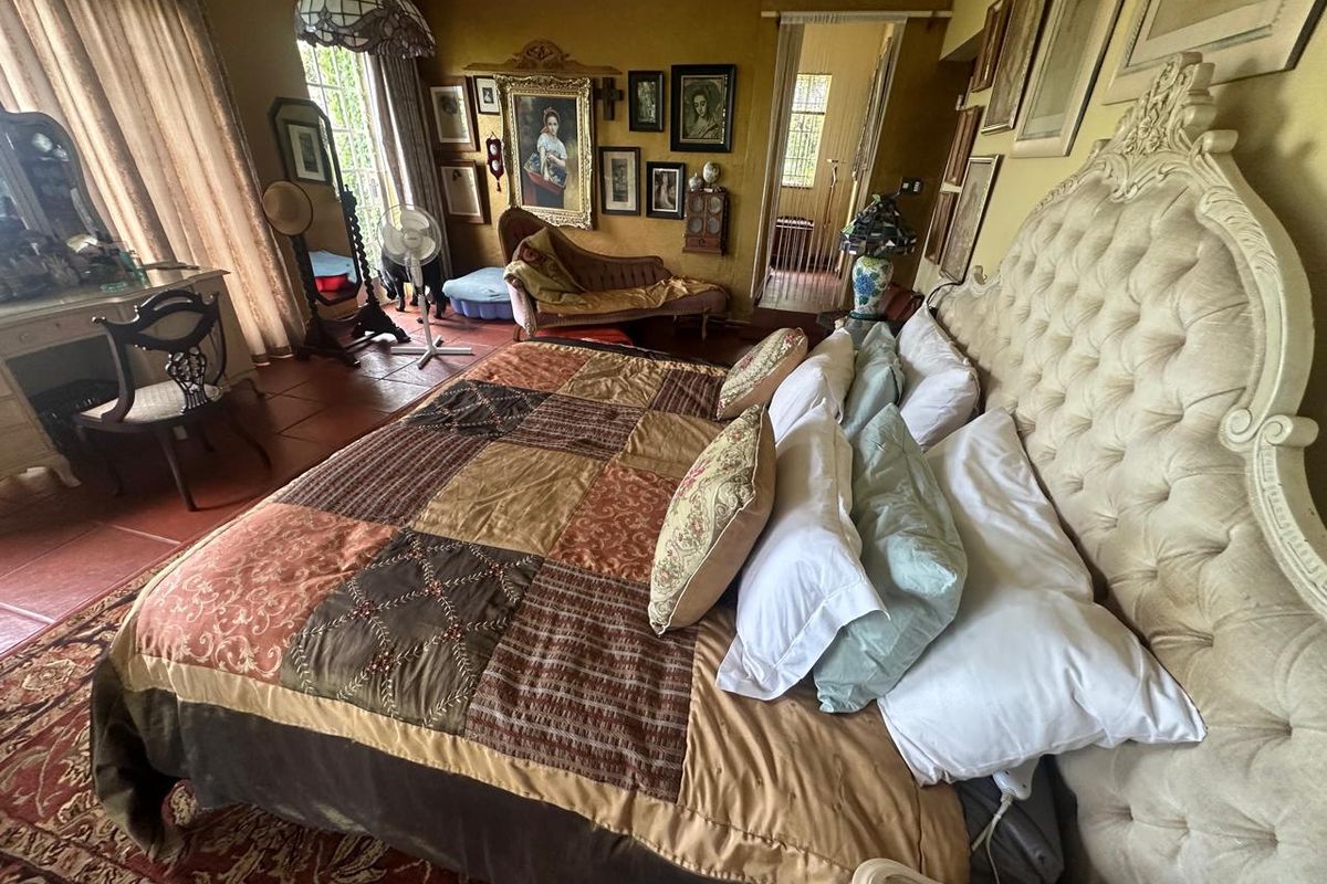 Spacious bedroom featuring tiled flooring and access to an adjoining room through a doorway, with large windows providing natural light.