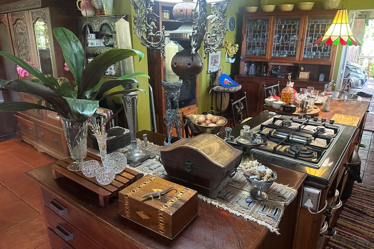 A traditional kitchen featuring a large wooden island with an integrated gas hob, ample cabinetry, and classic tiled flooring.
