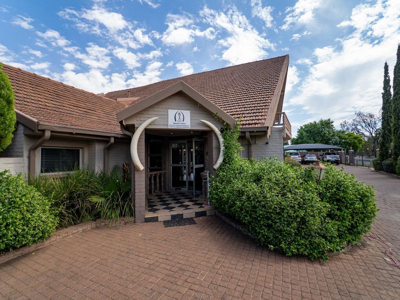 The front entrance of the guest house features a paved driveway, a tiled roof, and a distinctive covered entryway with decorative tusks.