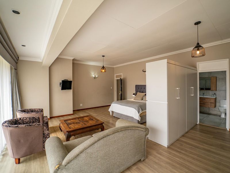 Spacious bedroom suite featuring laminate flooring, recessed lighting, a large built-in wardrobe, and an integrated en-suite bathroom.