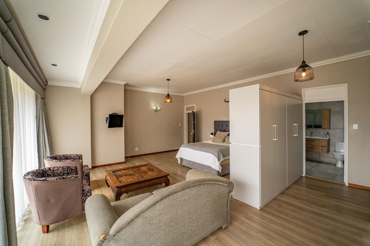 Spacious bedroom suite featuring laminate flooring, recessed lighting, a large built-in wardrobe, and an integrated en-suite bathroom.