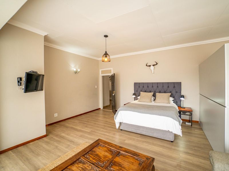 A spacious bedroom featuring light-toned laminate flooring, neutral wall finishes, and a built-in wardrobe, offering a clean and comfortable living space.