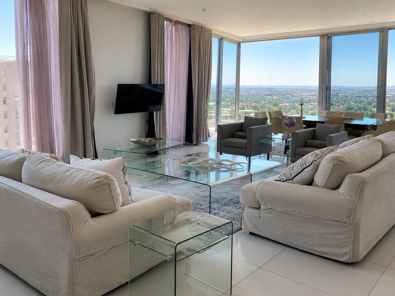 Spacious open-plan living and dining area featuring floor-to-ceiling windows with panoramic views, sleek tiled flooring, and modern recessed lighting.